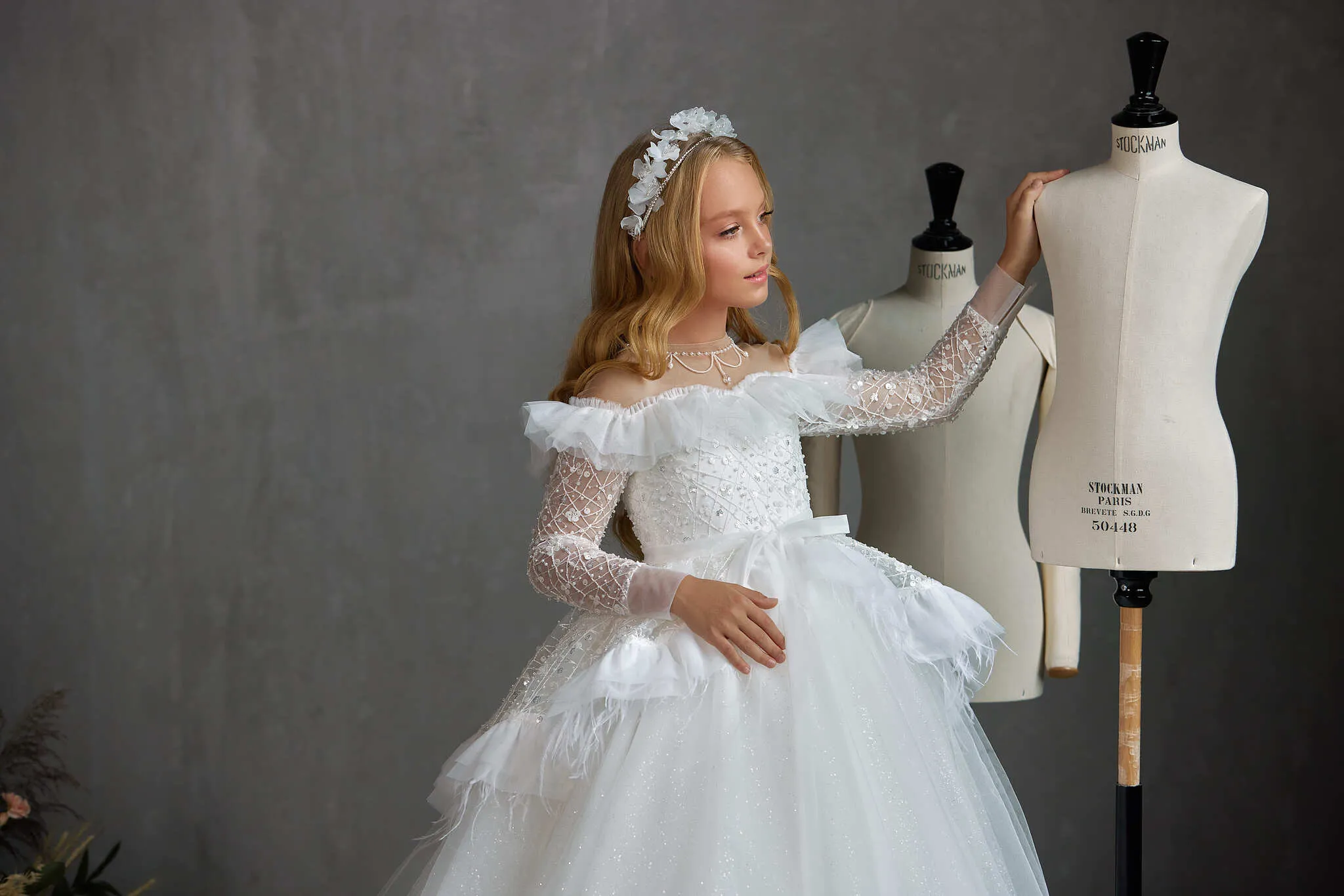 BOSTON – STRIKING OFF-THE-SHOULDER COMMUNION DRESS WITH RUFFLED FEATHER PEPLUM
